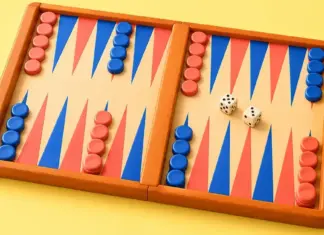Backgammon säännöt – lauta, siirrot ja voittaminen Värikäs backgammon-lauta, jolla on punaisia ja sinisiä pelinappuloita sekä kaksi noppaa keltaisella taustalla.
